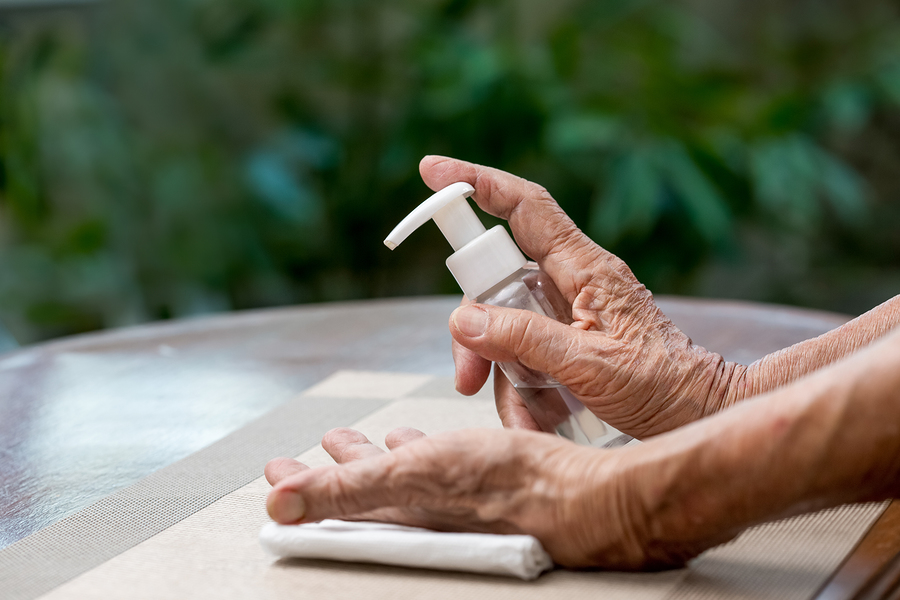 Elderly Woman Applying Alcohol Gel Cleaning Hands To Helping Pro