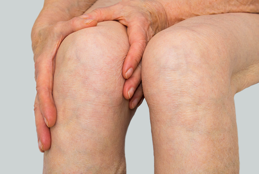 Senior Woman Holding The Knee With Pain On Gray