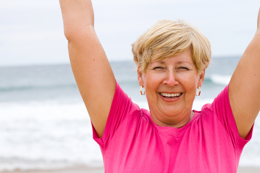 Happy Elderly Woman Doing Exercise On Beach