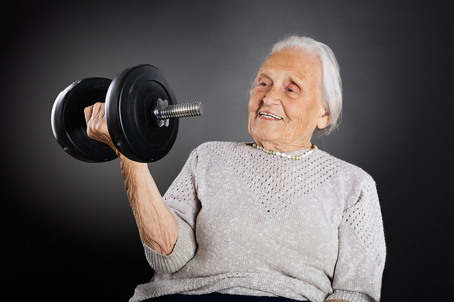 Happy Senior Woman Doing Exercise With Dumbbell Over Grey Background