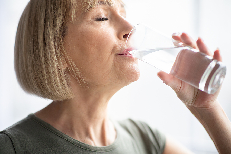 Portrait Of Sporty Mature Woman Drinking Water During Her Workou
