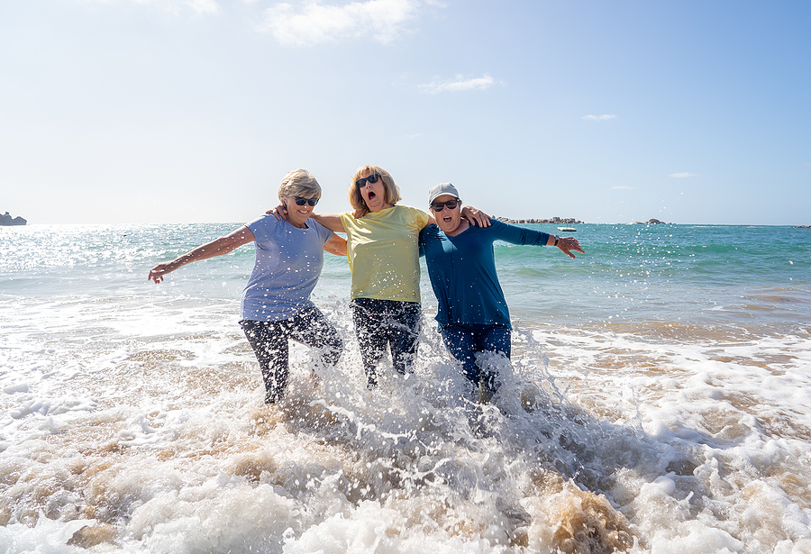 Group Of Three Senior Women Laughing As Falling Down In The Wate