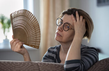 Exhausted Middle Aged Woman Waving Her Fan, Suffering From Menop