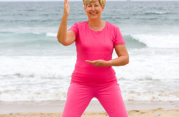 Happy Senior Woman Doing Exercise On Beach
