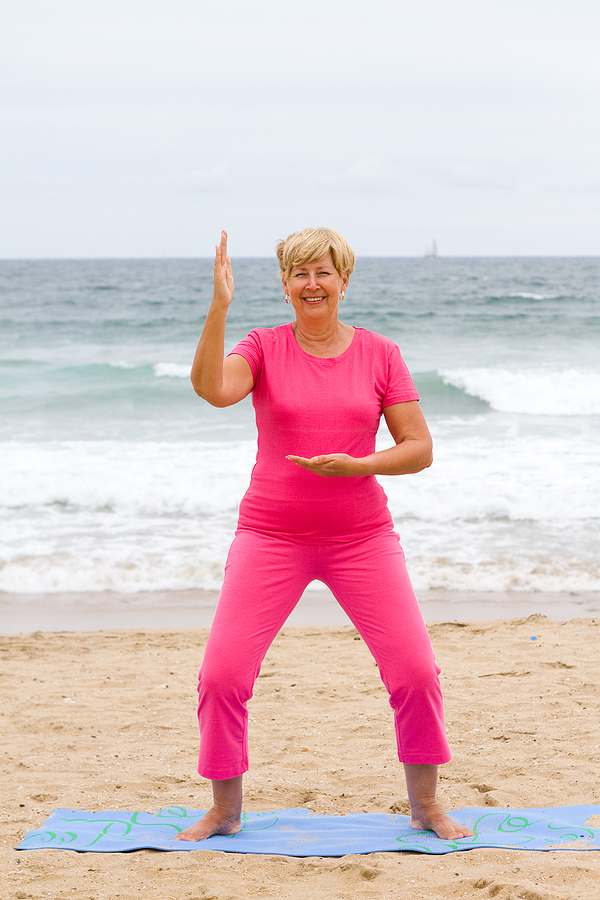 Happy Senior Woman Doing Exercise On Beach